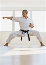 Hispanic male karate black belt in fighting stance.