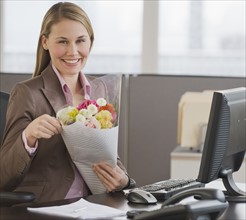 Businesswoman holding bouquet of flowers.