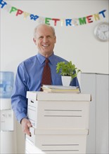 Retiring senior businessman carrying boxes .