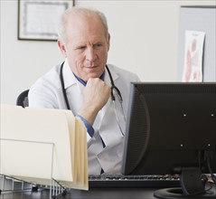 Senior male doctor looking at computer.
