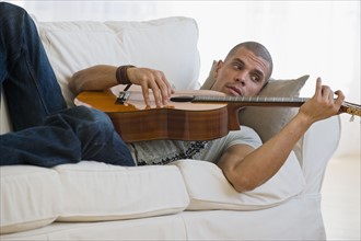Hispanic man playing guitar.