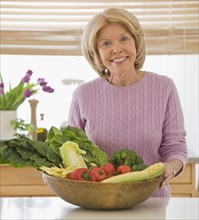 Senior woman holding bowl of vegetables.