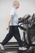 Senior man walking on treadmill.