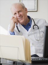 Senior male doctor sitting at desk.