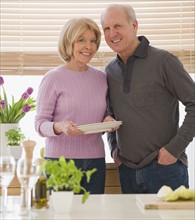 Senior couple with dishes in kitchen.