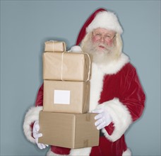 Santa Claus holding stack of packages.