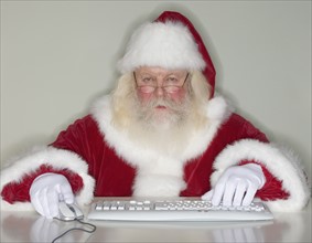 Santa Claus typing on computer.