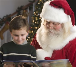 Santa Claus and boy reading book.