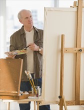 Senior man painting on easel.
