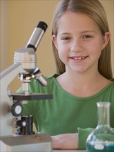 Girl in science class next to microscope.