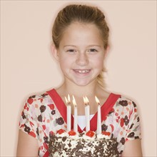 Girl holding birthday cake with lit candles.