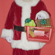 Santa Claus holding shopping basket with gifts.