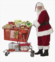 Santa Claus pushing shopping cart full of gifts.