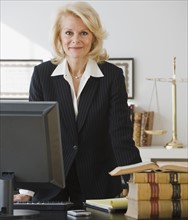 Businesswoman leaning on desk.