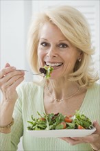 Senior woman eating salad.