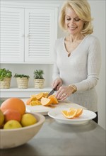 Senior woman cutting oranges.