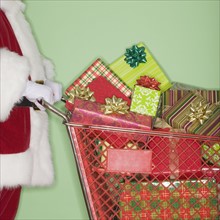 Santa Claus pushing shopping cart of gifts.