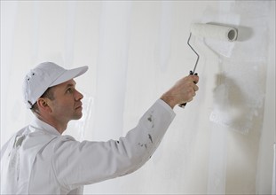 Male painter painting with paint roller.