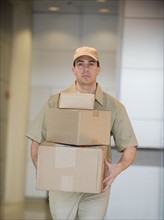 Delivery man carrying stack of packages.