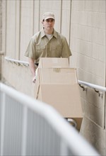 Delivery man pushing stack of packages.