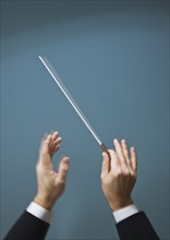 Male conductor’s hands with baton.