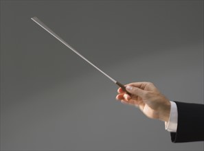 Male conductor’s hand holding baton.