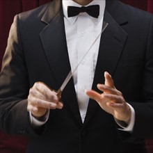 Male conductor holding baton.