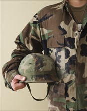 Male soldier holding helmet.