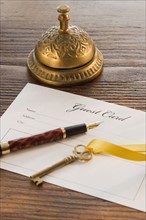 Guest registry card, pen, key and bell on table.