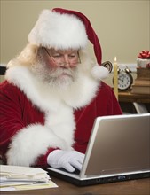 Santa Claus looking at laptop.
