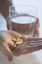 Man holding medication and glass of water.