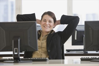 Businesswoman with hands behind head.