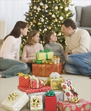 Family with gifts in front of Christmas tree.