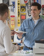 Hardware store sales clerk handing over purchase.