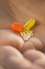 Close up of open medication capsule in man’s hand.