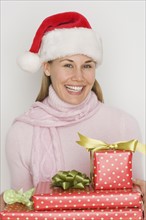 Woman in Santa Claus hat holding gifts.