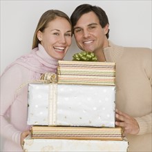 Couple holding pile of gifts.