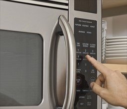 Man pushing button on microwave.