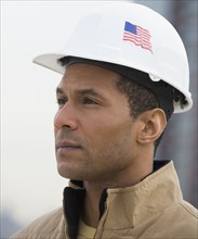 African male construction worker with American flag on hard hat.