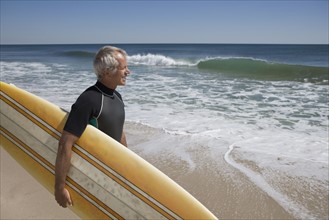 Man holding surfboard at beach.