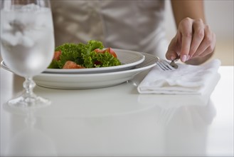 Woman lifting fork next to plate of food.