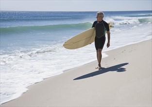 Man carrying surfboard at beach.