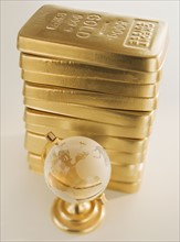 Globe next to stack of gold bars.