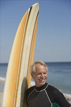 Man next to surfboard at beach.