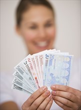 Woman holding fanned out euro banknotes.