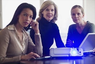 Multi-ethnic businesswomen next to projector.