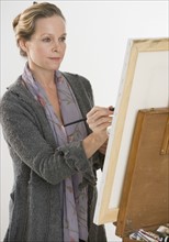 Woman painting at easel.