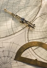 Protractor and drafting compass on antique map.