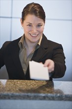Customer service representative handing ticket over counter.
