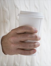 Close up of man holding take out coffee.